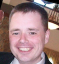 a man in a suit and tie smiling at the camera