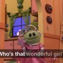 a green frog in a pink dress in a kitchen