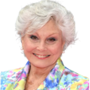 an older woman with white hair wearing a colorful jacket