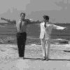 a couple of men standing on top of a sandy beach