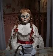 a creepy doll sitting at a table with a cup
