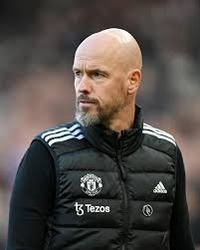 a bald man in a black jacket on a soccer field