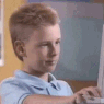 a young man sitting at a desk using a laptop computer