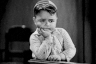 a black and white photo of a young boy sitting at a table